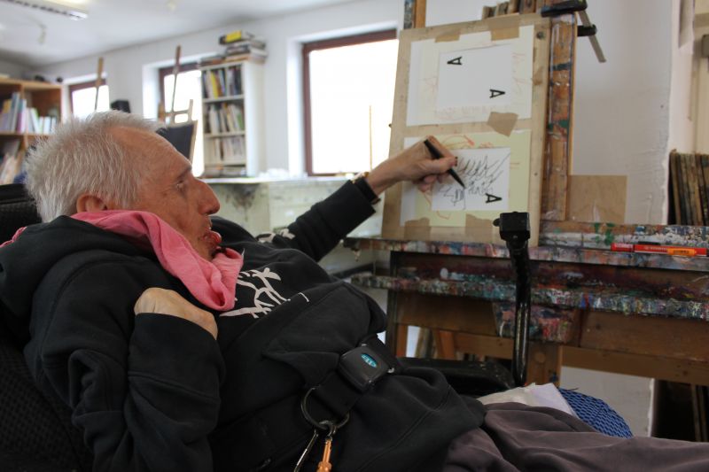 Maler im Rollstuhl zeichnet an der Staffelei